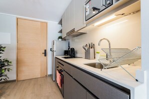 A modern kitchen with a built-in oven, a sink, and a stainless steel faucet. - Comfortable Studio Apartment in Nunoa Ideal for 2 (Ñuñoa)