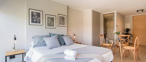 A modern bedroom with a large bed, bedside tables, a desk, and a chair.
