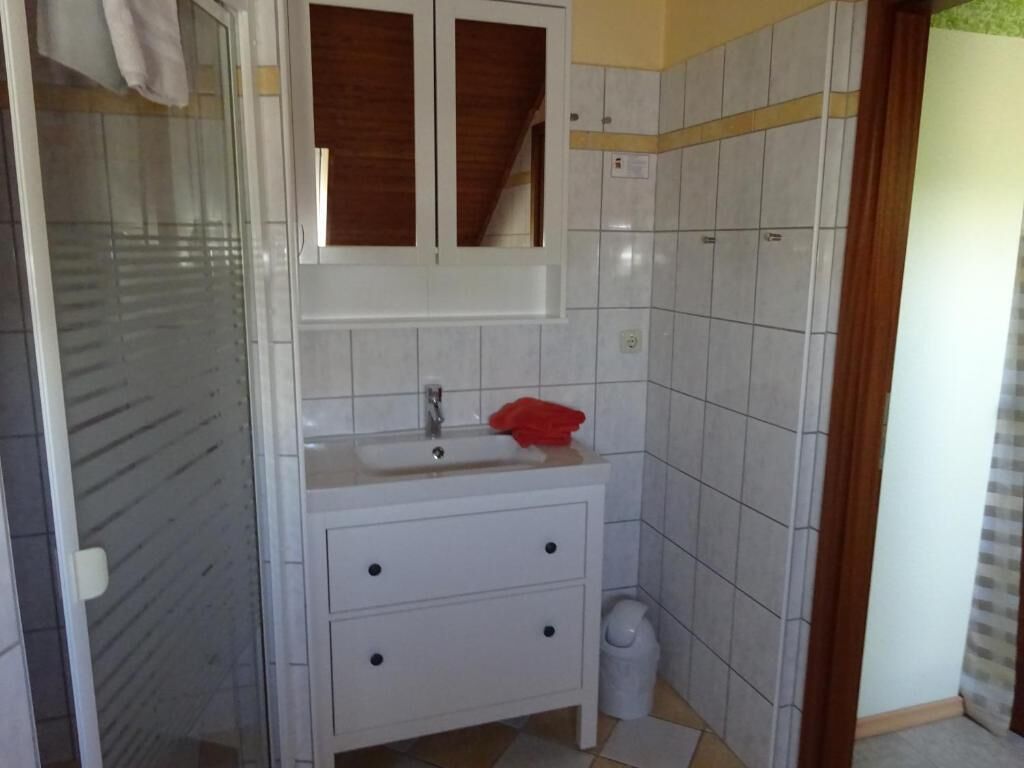 Un baño con tocador blanco, espejo y pared de azulejos.