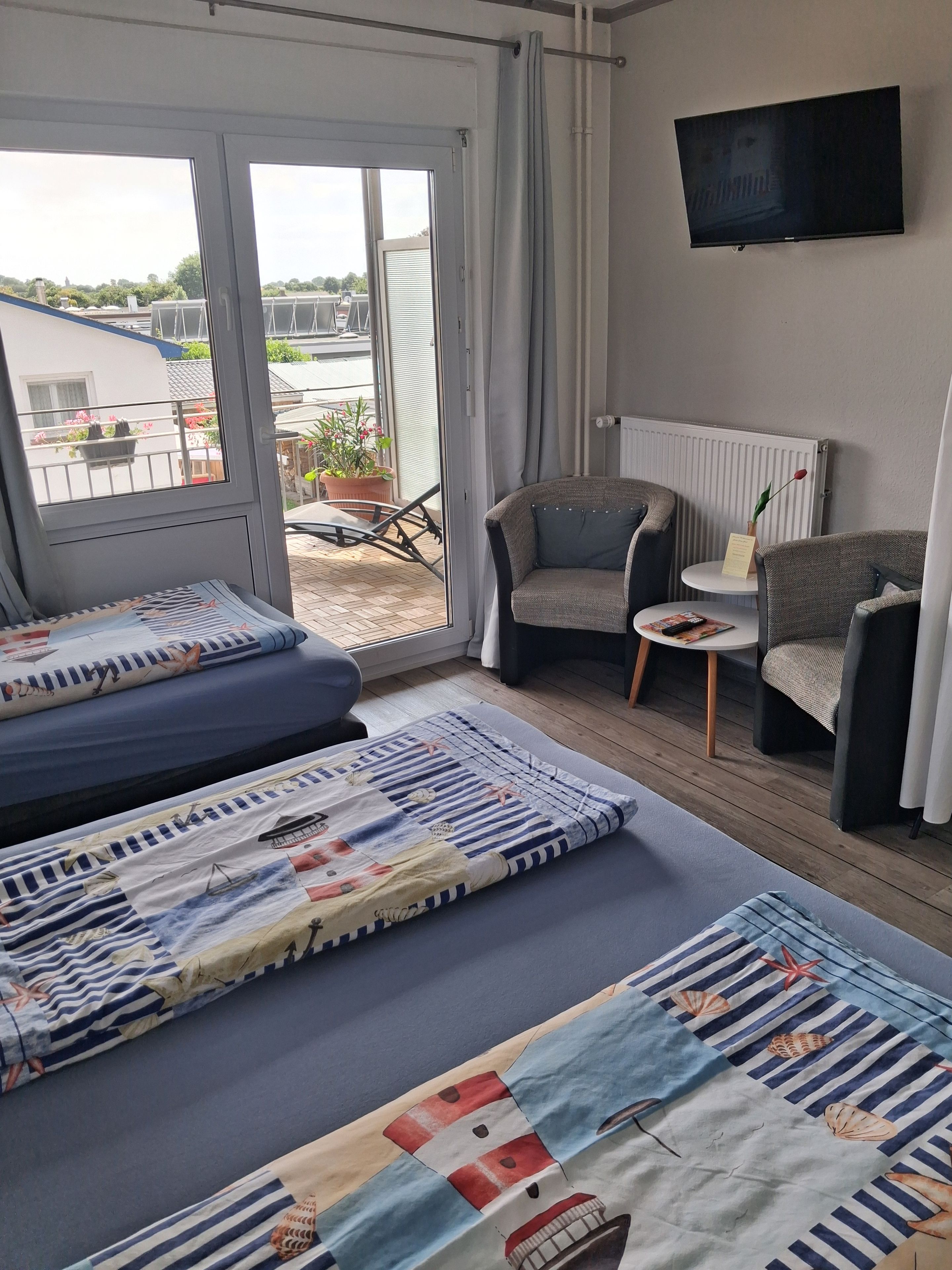 Een hotelkamer met een groot bed, een bank, een stoel, een klein tafeltje en een televisie aan de muur.