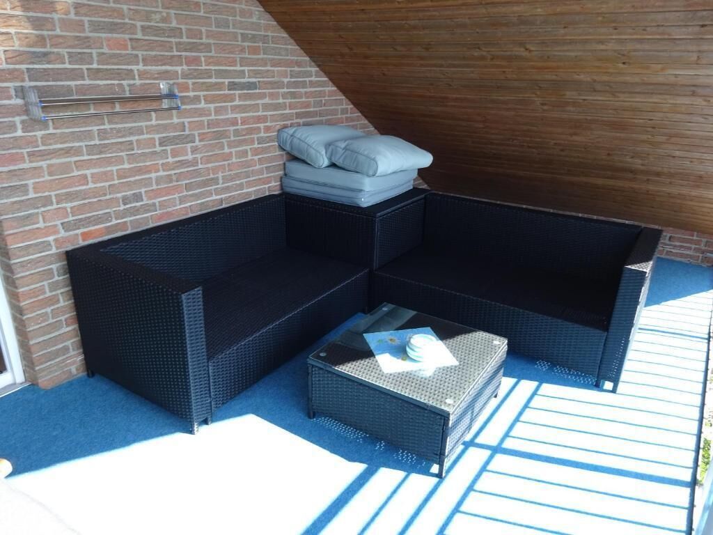 A corner seating area with a cushioned bench and a small table, a wicker basket, and a metal rack against a brick wall.