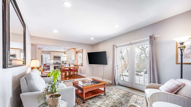 A living room with a sofa, armchair, coffee table, and a potted plant. There is a dining area with a table and chairs, and a kitchen in the background. - ‼️Lovely Ann Arbor Retreat Near Parks & Shops (Ann Arbor)