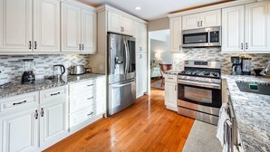 A modern kitchen with white cabinetry, stainless steel appliances, and a wooden floor. - ‼️Lovely Ann Arbor Retreat Near Parks & Shops (Ann Arbor)