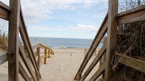 Una pasarela de madera que bordea la playa y llega al océano.