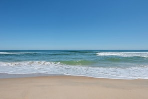 A beach with waves, clear sky, and sandy shore.