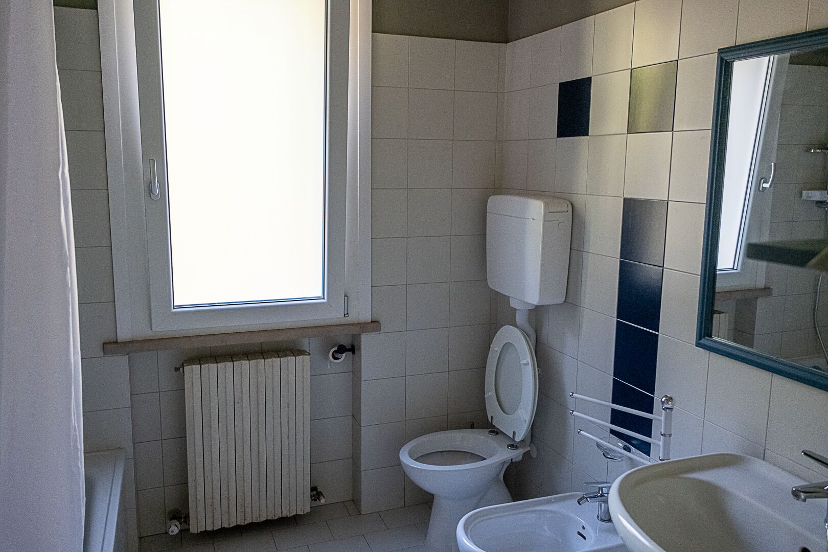 Een badkamer met toilet, wastafel en raam.