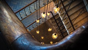 A spiral staircase with hanging light fixtures and a brick floor.