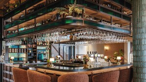 A bar area with multiple shelves, hanging glasses, and bar stools.