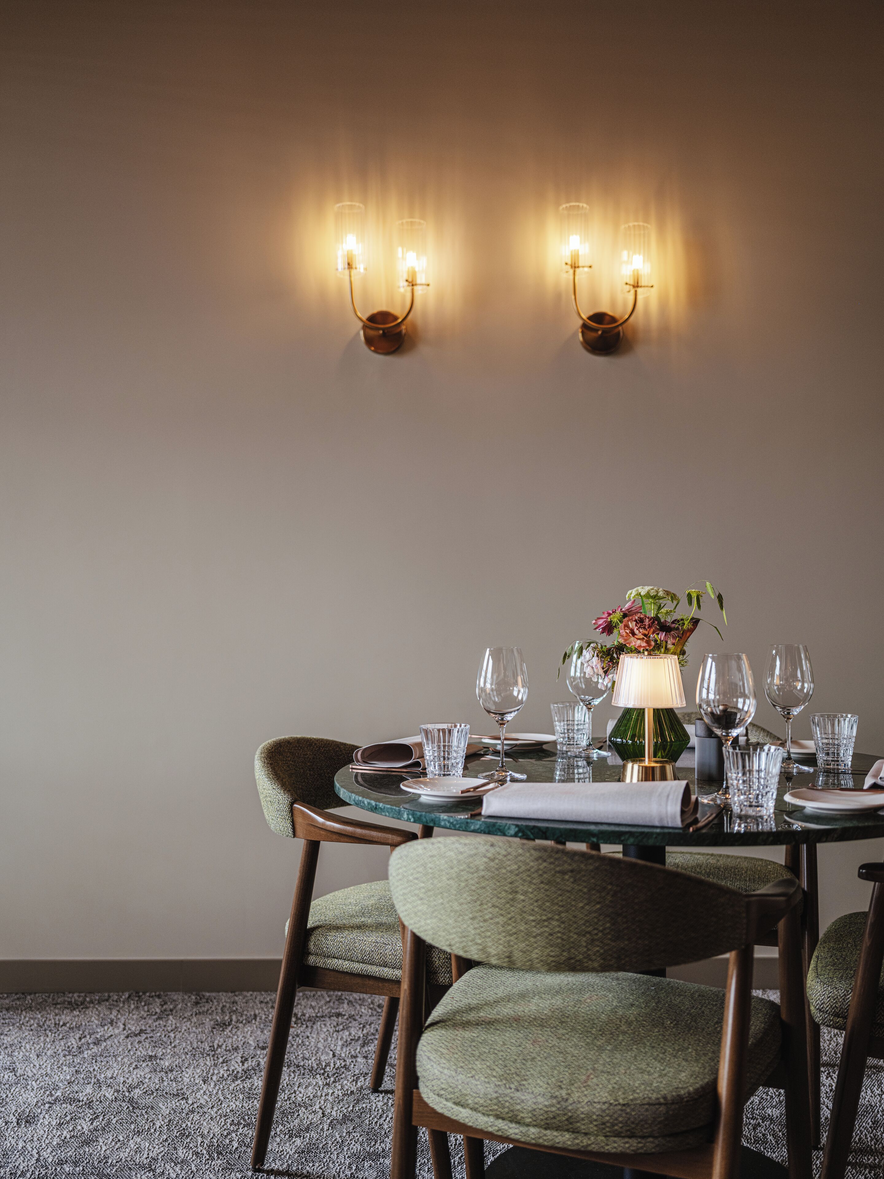 A dining area with a round table set for four, surrounded by upholstered chairs.