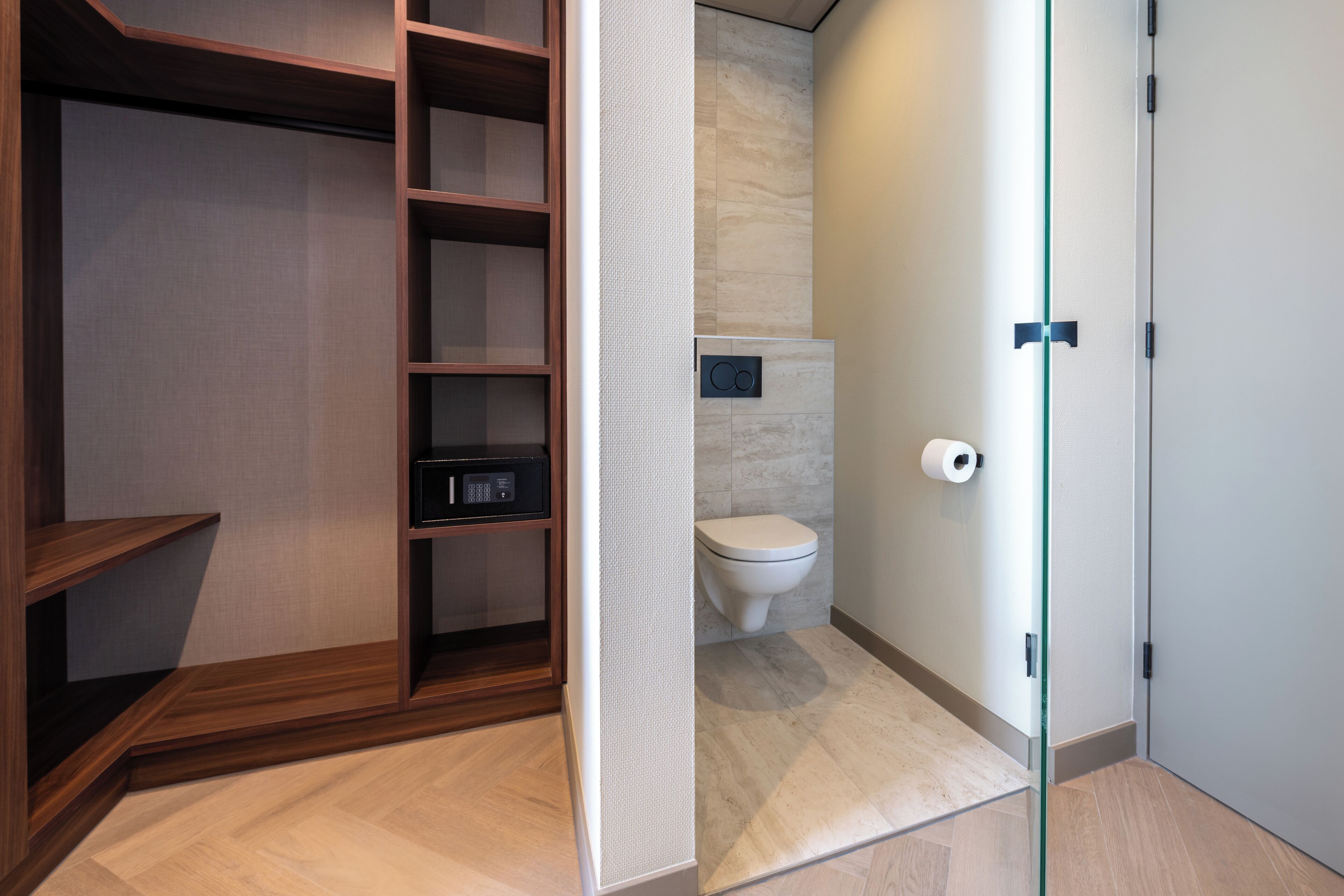 Een moderne badkamer met toilet, een inbouwkast en een glazen scheidingswand.