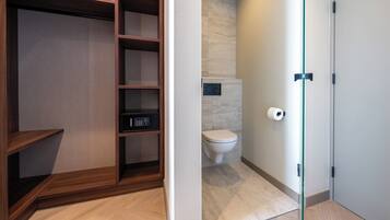 Een moderne badkamer met toilet, een inbouwkast en een glazen scheidingswand.