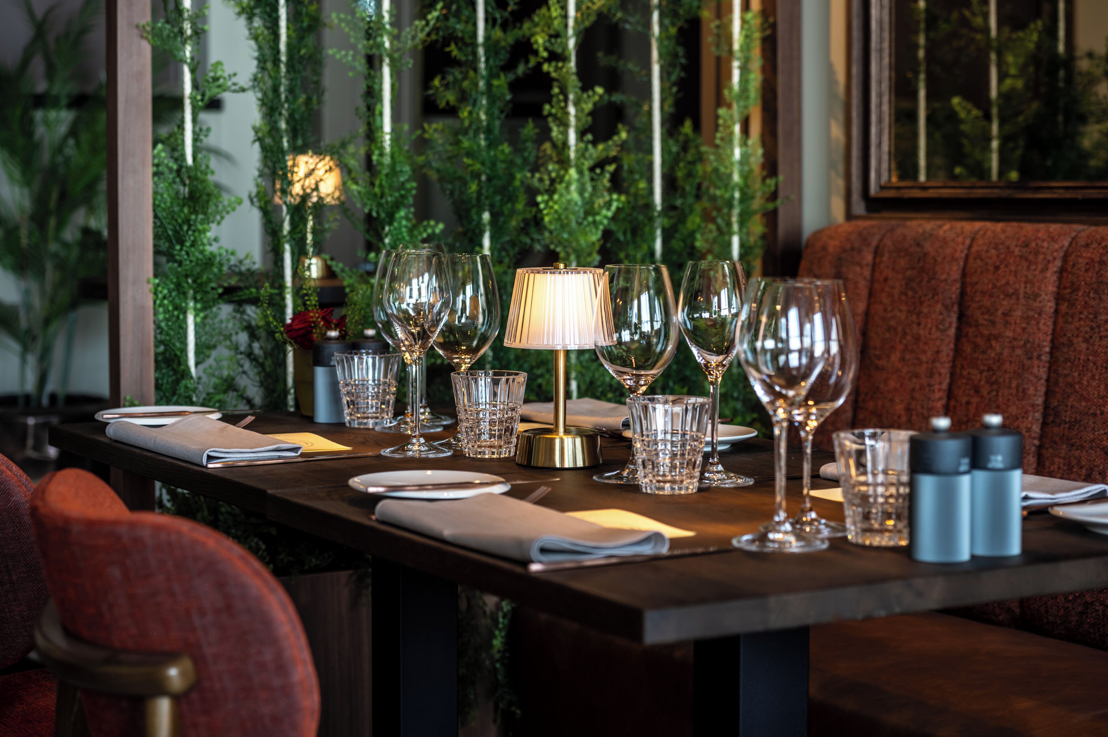 A dining table set with wine glasses, a lamp, and salt and pepper shakers.