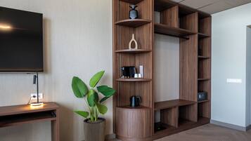 Een moderne woonkamer met een flatscreen televisie, houten planken, een potplant en een koffiezetapparaat.