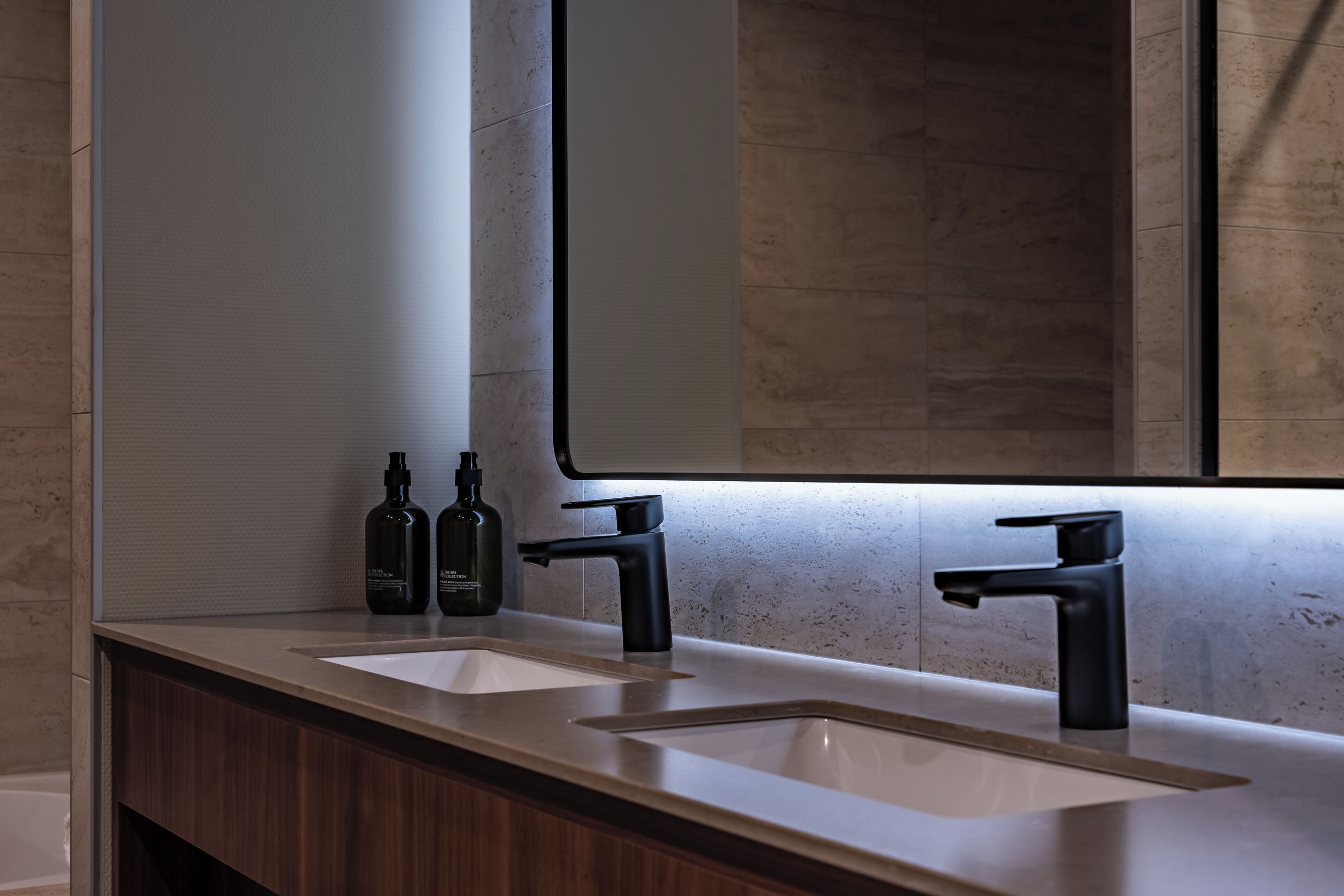 A modern bathroom with two sinks, a large mirror, and a wooden vanity.
