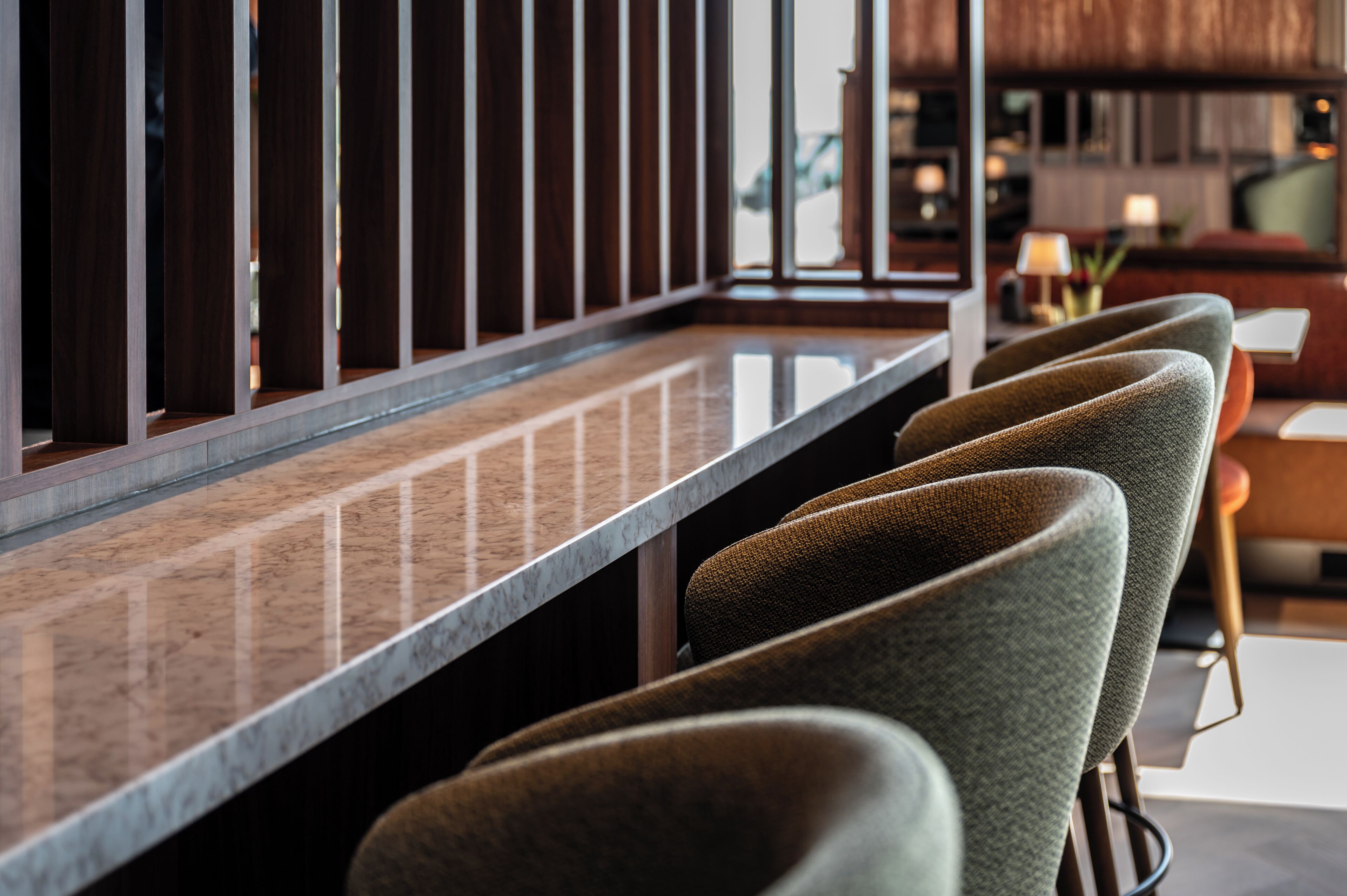 A bar area with a long counter and multiple bar stools.