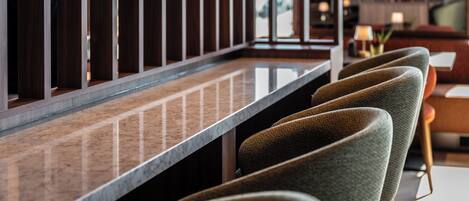 A bar area with a long counter and multiple bar stools.