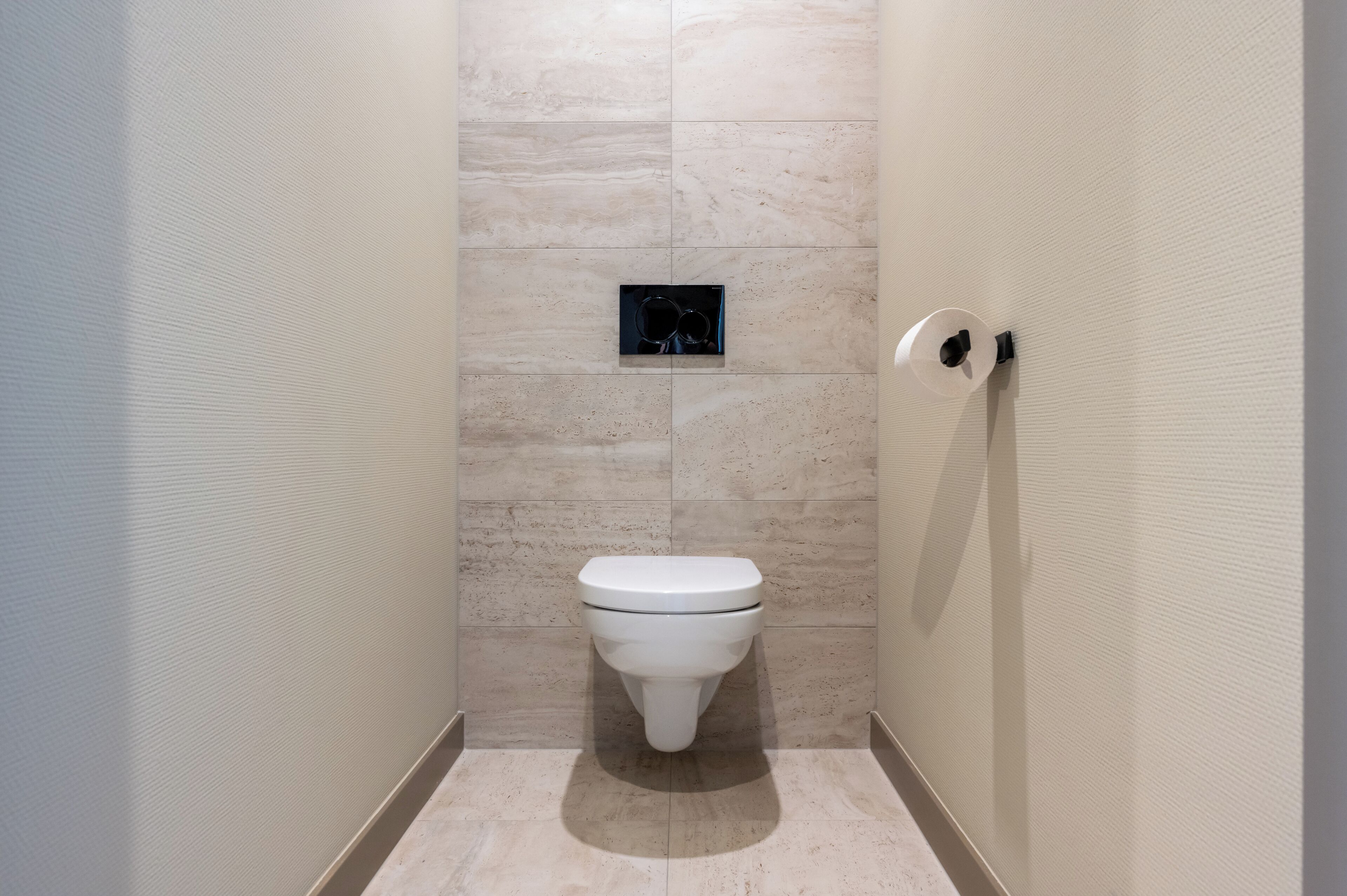 Un bagno moderno con un water, un bidet a muro e un piccolo cestino.