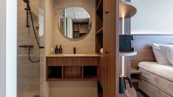 A modern bathroom with a shower, a sink, a mirror, and a built-in shelf.