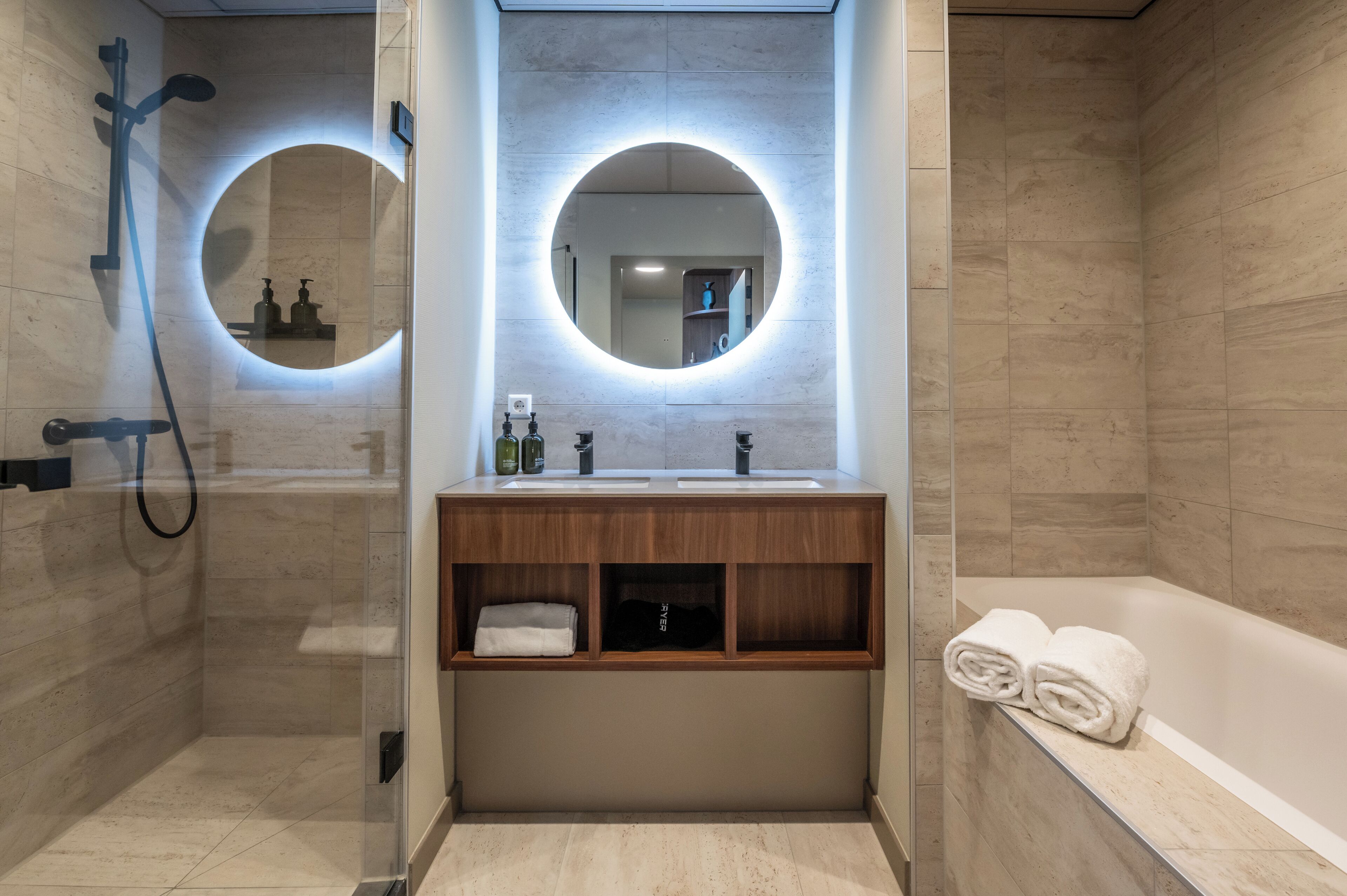 A modern bathroom with a glass-enclosed shower, a wooden vanity with a mirror, and a bathtub.