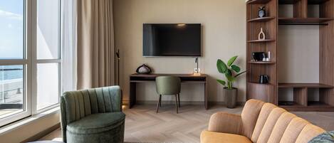 A modern living room with a sofa, armchair, and a desk with a TV.