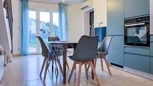 Een moderne keuken met een eethoek, met een tafel met stoelen, een koelkast en een oven.