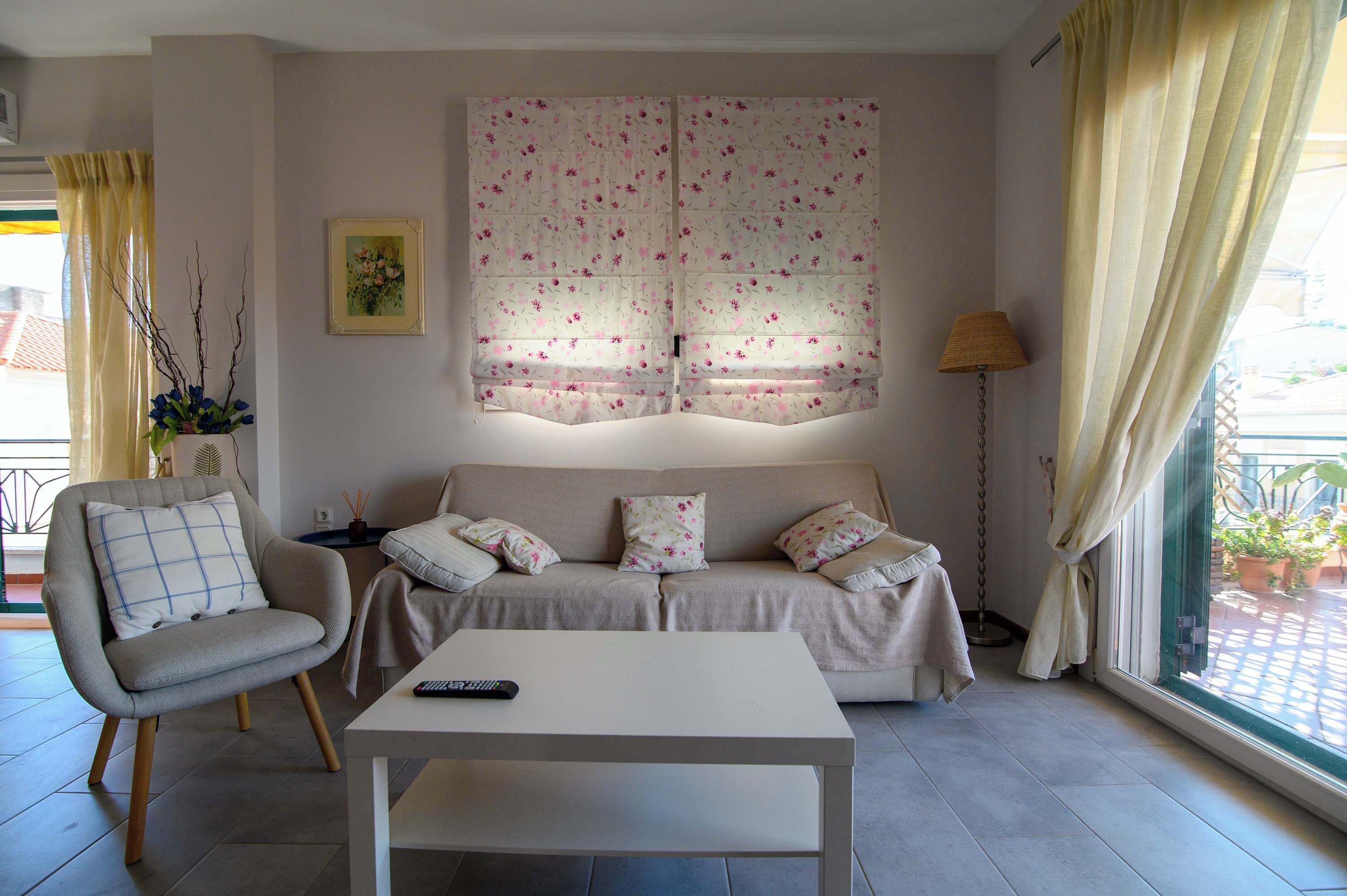 A living room with a sofa, a chair, a coffee table, and a window with curtains.
