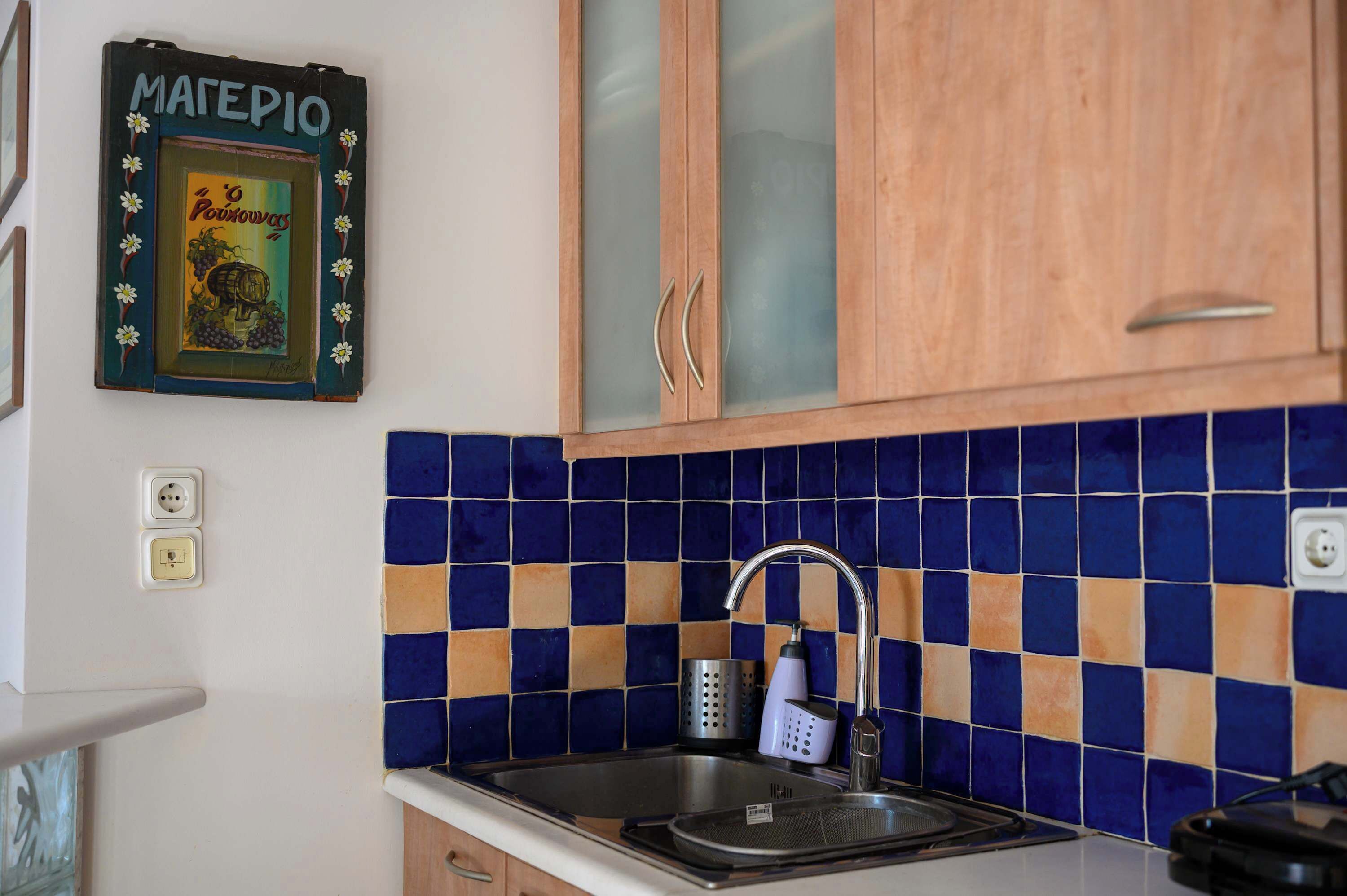 A kitchen with a tiled backsplash, a stainless steel sink, and wooden cabinets.