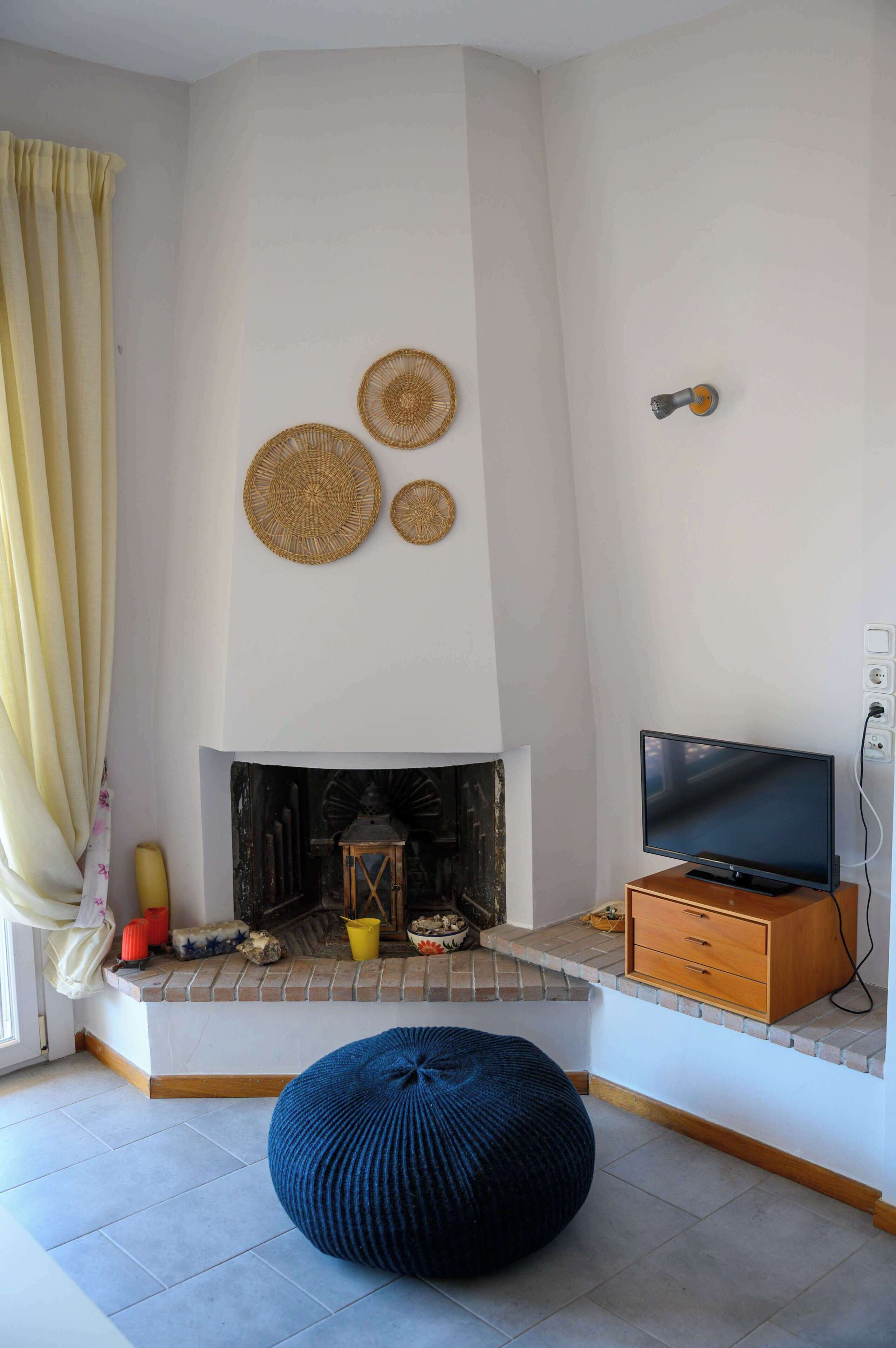 A living room with a fireplace, television, and a blue bean bag.