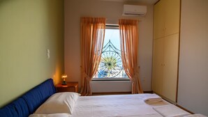 Une chambre à coucher avec un lit, des rideaux, une fenêtre donnant sur un beau paysage, un climatiseur et une lampe de chevet.