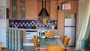 Une cuisine avec des meubles en bois, un îlot central en verre, un réfrigérateur blanc et une table à manger avec des chaises.