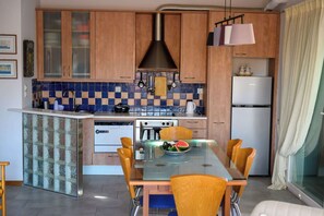 A kitchen with wooden cabinets, a glass island, a white refrigerator, and a dining table with chairs.