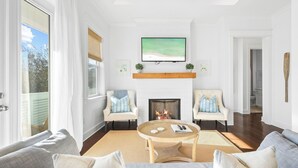 A living room with a fireplace, two armchairs, a sofa, and a coffee table. - ForShore30A - Prominence - Low-speed vehicle,Bunk Room,Large Heated Resort Pool (Panama City Beach)