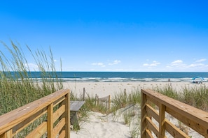 A wooden boardwalk leading to a beach with sand dunes and grass. - Shell Yeah- Ocean Isle Beach (Ocean Isle Beach)