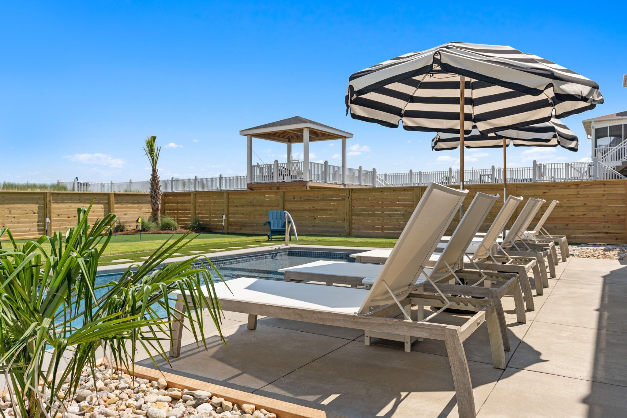 A pool area with lounge chairs and a gazebo.