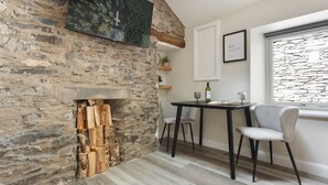 Eine rustikale Steinwand mit Kamin, einem Esstisch mit Stühlen und einem gerahmten Bild.