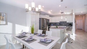 A modern kitchen with white cabinetry, stainless steel appliances, and a central island. - Modern Condo Near Disney (Kissimmee)
