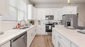 Una cocina moderna con armarios blancos, electrodomésticos de acero inoxidable y una isla central.