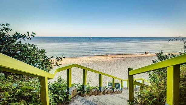A staircase leading to a beach with a clear view of the ocean. - Feriendorf Fynnus (Dranske)