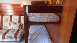 A bunk bed room with a wooden headboard, a lower bunk with a white mattress, and a top bunk with a white mattress. - Studio at the foot of the slopes for 6 people Le Bois d'Aurouze (Dévoluy)