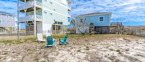 Una propiedad frente a la playa con un edificio de varios pisos, asientos al aire libre y un paisaje arenoso.
