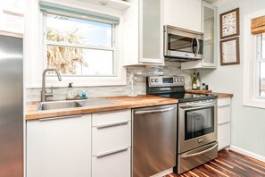 Een moderne keuken met roestvrijstalen apparatuur, een houten aanrecht en een raam met uitzicht op palmbomen.