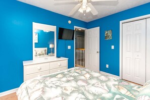 Un dormitorio con cama, cómoda, espejo y una puerta que da a un pasillo.