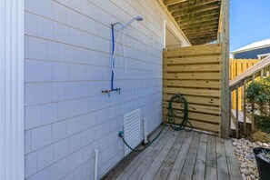 Eine Holzterrasse mit einer weiß gefliesten Wand, einem Holzzaun und einem grünen Schlauch.