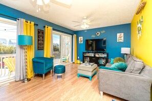 A living room with a blue wall, a ceiling fan, a television, and a sofa.