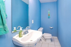 Une salle de bain avec un lavabo blanc, des toilettes et un mur bleu.
