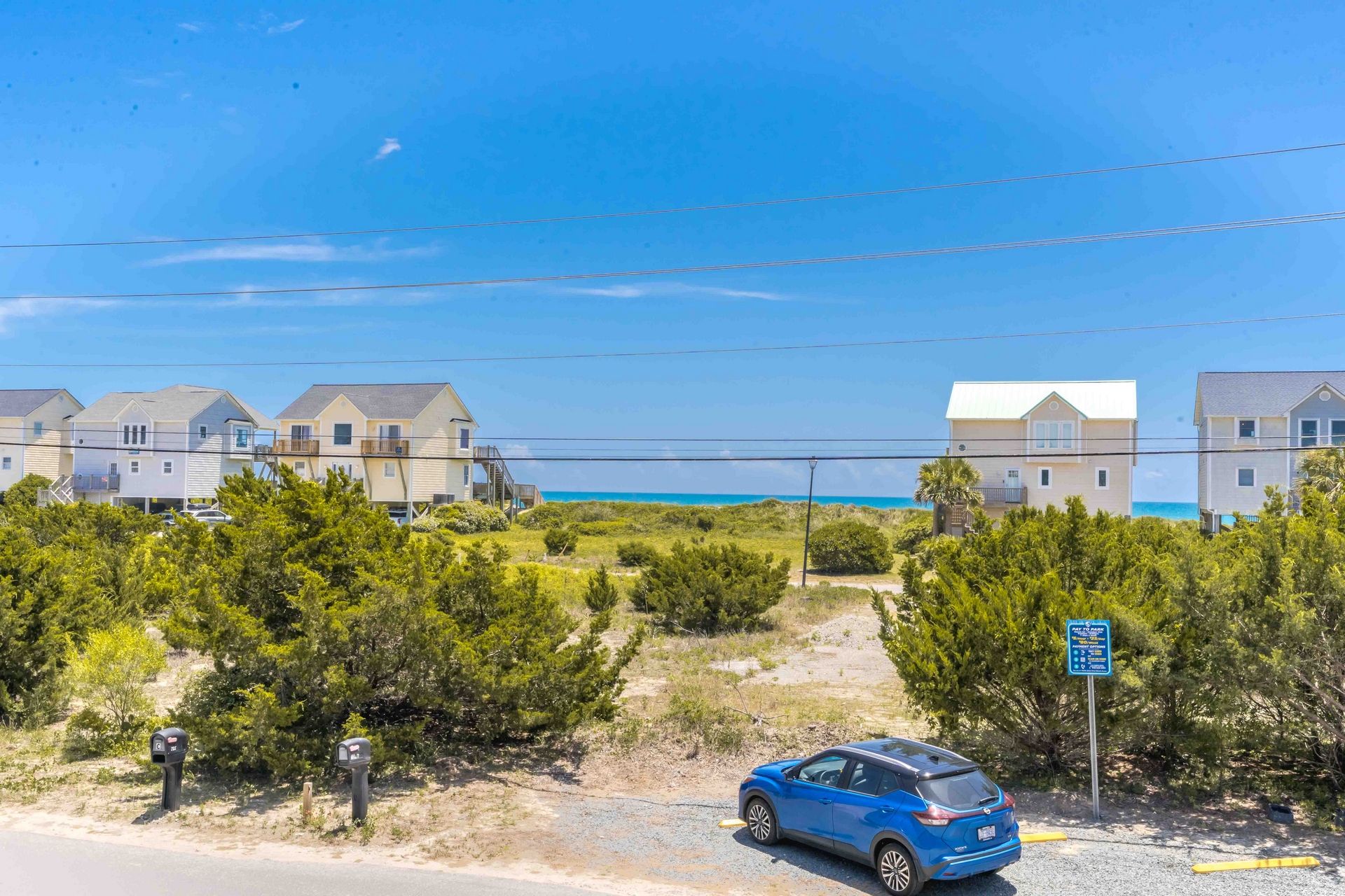 A coastal residential area with houses, a parking area, and a clear view of the ocean.