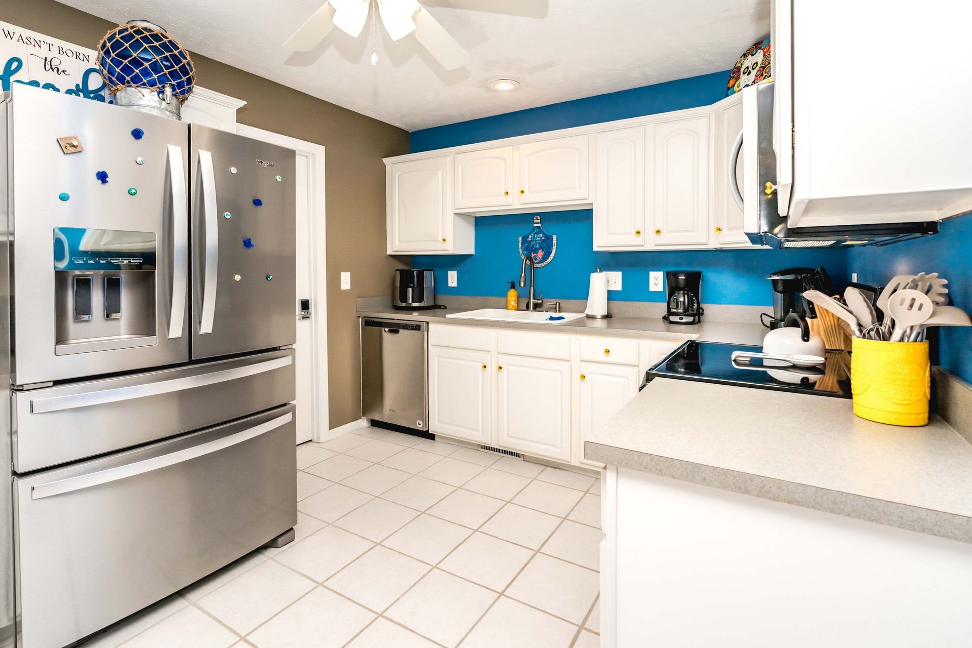 A modern kitchen with stainless steel appliances, white cabinets, and a blue accent wall.