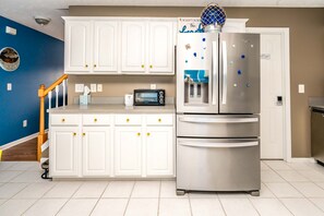 A kitchen with white cabinets, a stainless steel refrigerator, a toaster, and a microwave.