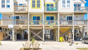 A multi-story beachfront building with balconies, a basketball hoop, and outdoor seating.
