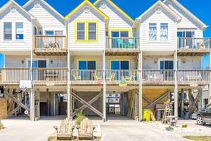 A multi-story beachfront building with balconies, a basketball hoop, and outdoor seating.